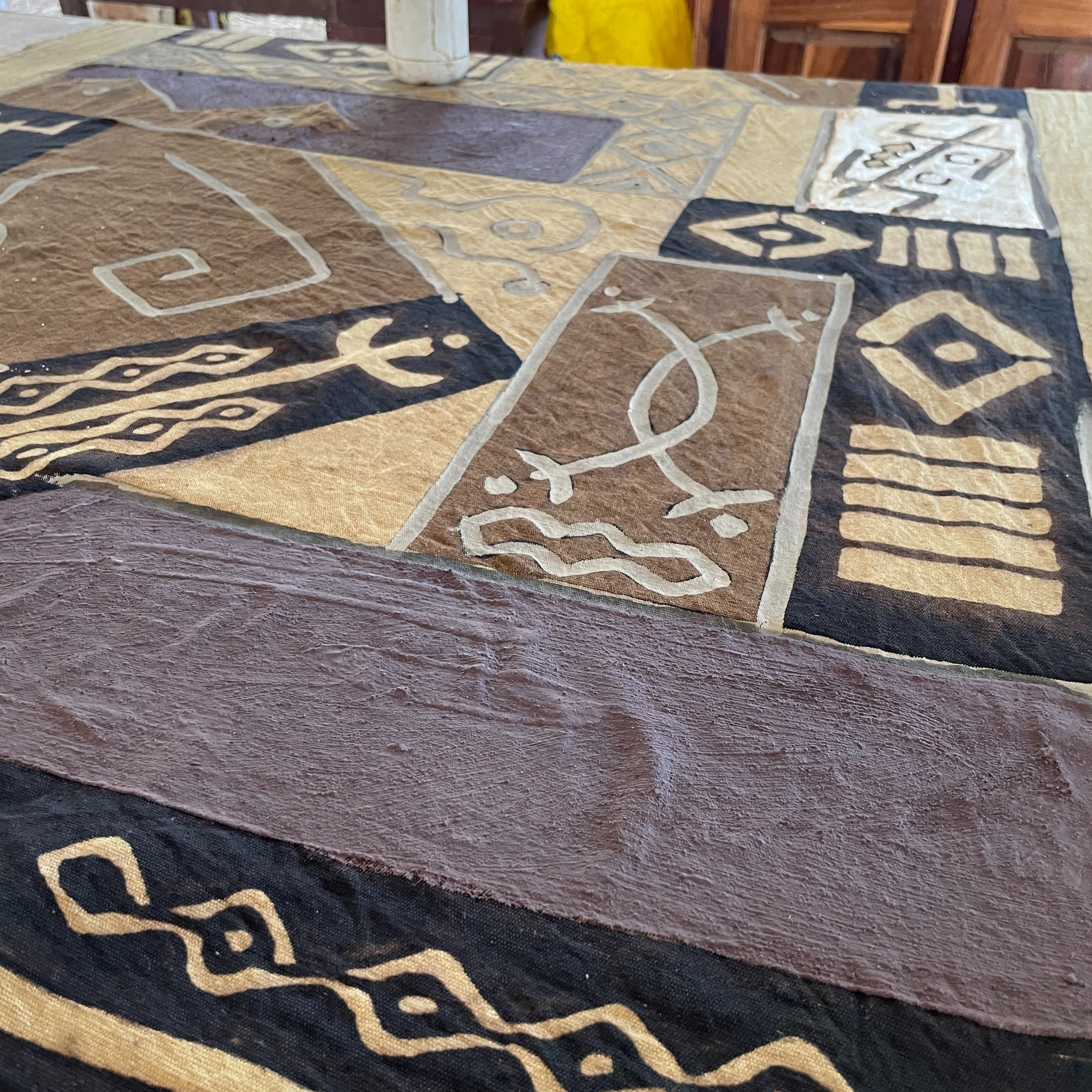 une étoffe sur une table entrain de sécher avec des motifs en bogolan du Mali 